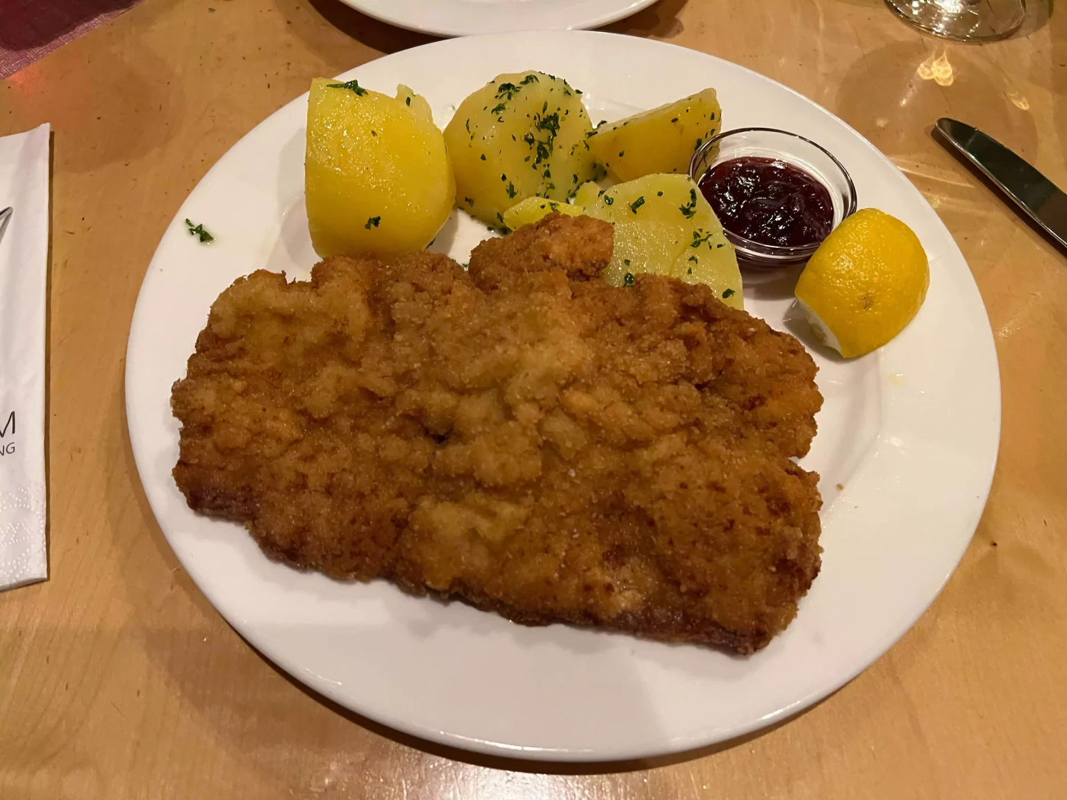 Traditional Austrian Wiener Schnitzel served at Braurestaurant IMLAUER in Salzburg, Austria, featuring tender slices of pork with rich gravy, accompanied by traditional sides like potatoes and seasonal vegetables. The warm, rustic plating reflects classic Austrian comfort food.