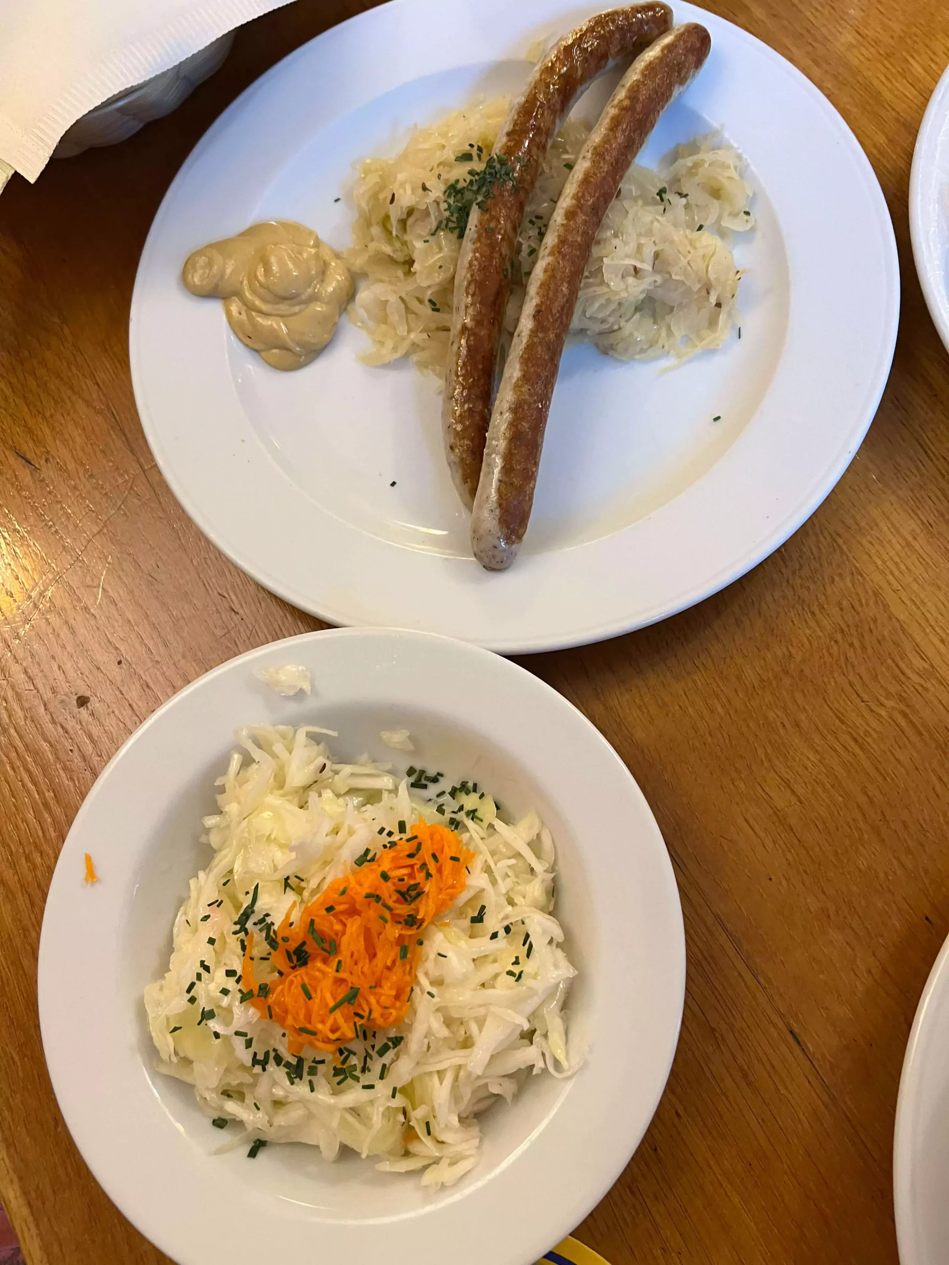 A traditional plate of sausages and sauerkraut served at Augustiner Bräugasthof Krimpelstätter in Salzburg, Austria. The juicy sausages are nestled beside a generous helping of tangy, slow-cooked sauerkraut, offering a classic Austrian comfort meal.