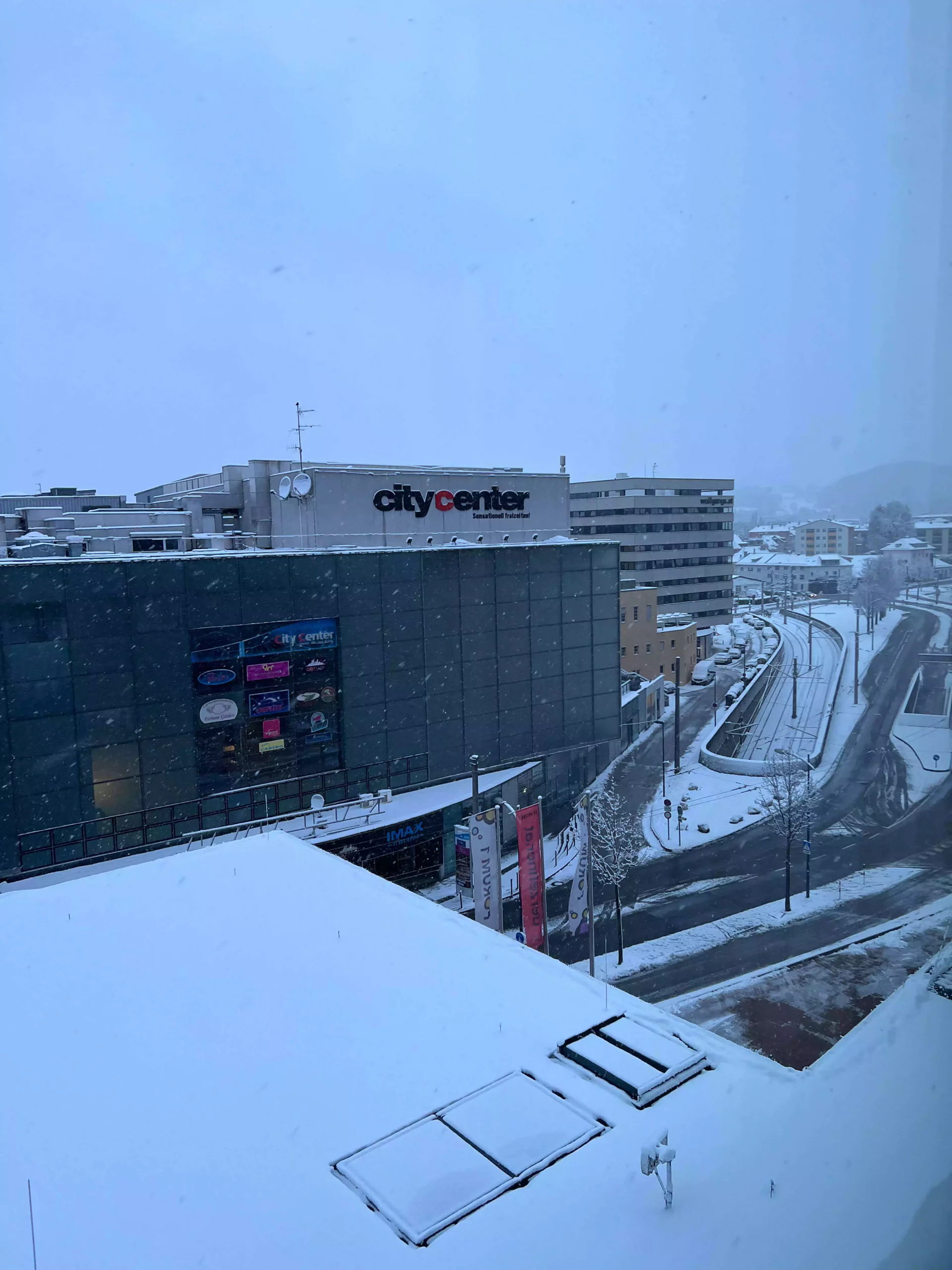 A serene snowy morning in Salzburg, Austria, with the city center’s rooftops blanketed in fresh white snow. The soft light and quiet streets below create a peaceful, postcard-perfect winter scene.