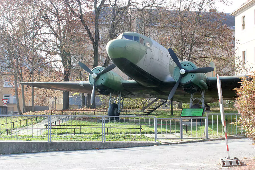 Historic military plane displayed at the Slovak National Uprising Memorial in Banská Bystrica, Slovakia, set outdoors near the museum’s bold modernist structure