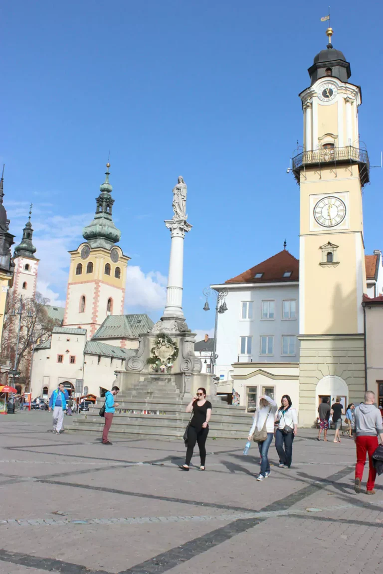 The Mariensäule (Mary Column) in Banská Bystrica, Slovakia, a Baroque-style monument featuring a statue of the Virgin Mary atop a tall pedestal, surrounded by ornate stone figures in the town square