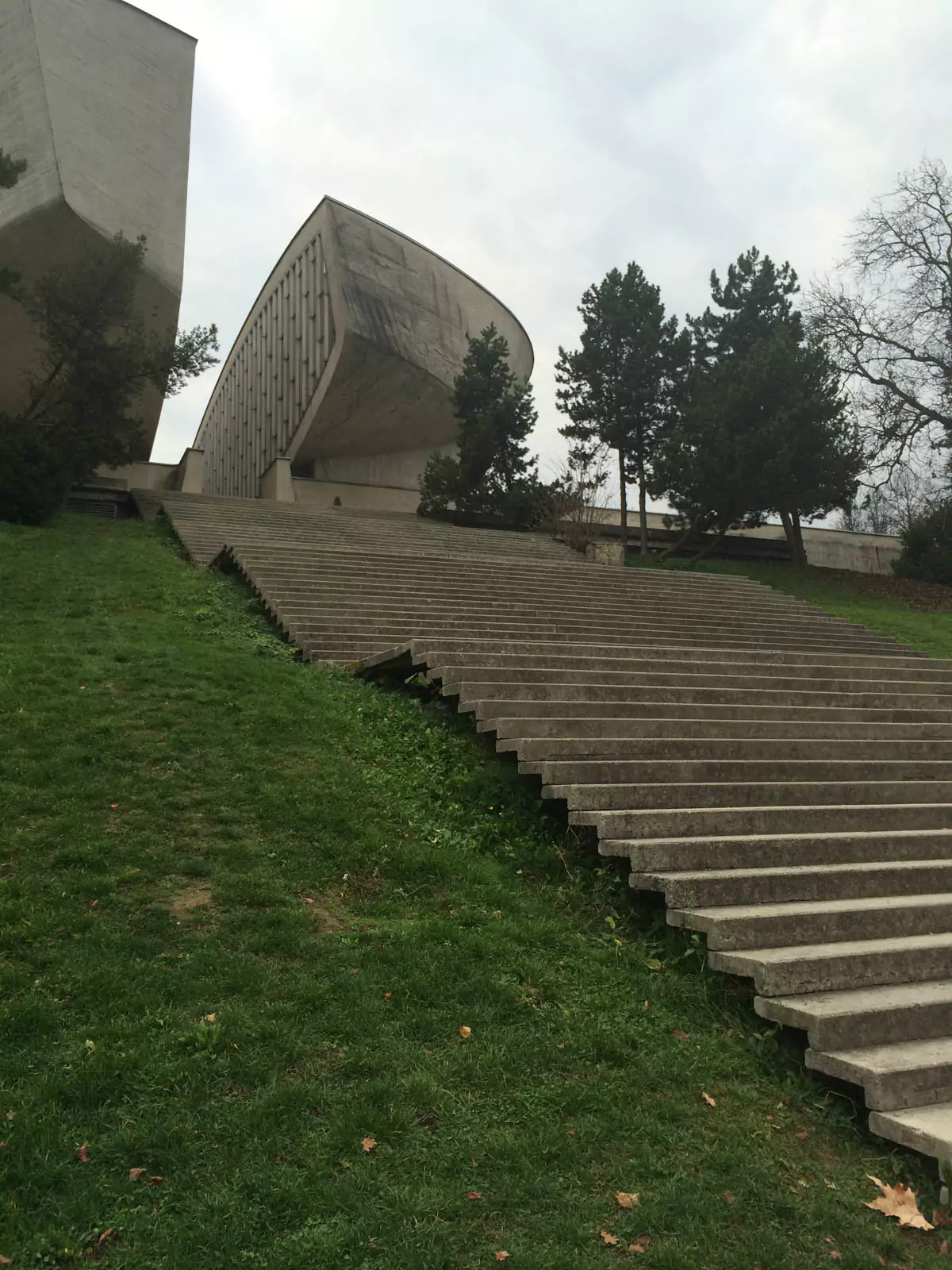 The Museum of the Slovak National Uprising in Banská Bystrica, Slovakia, with its striking split concrete structure symbolizing resistance, surrounded by flags and war memorials