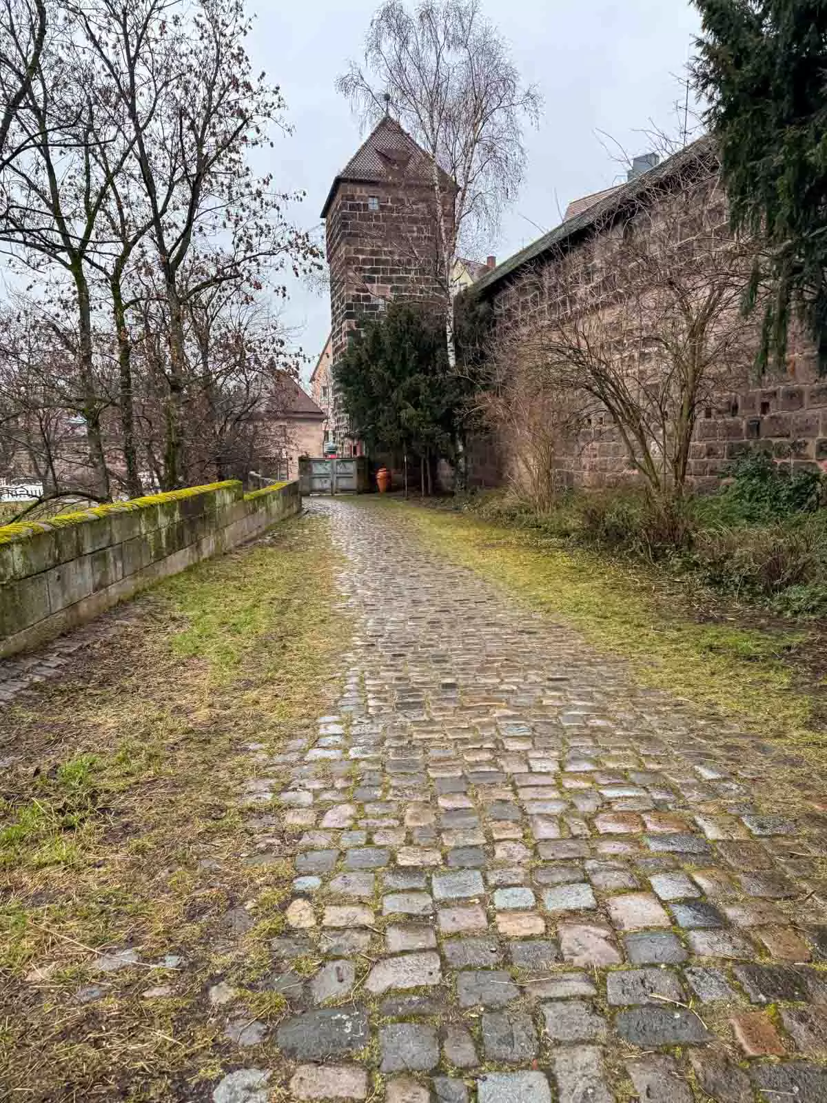 View of the south entrance to Nuremberg’s Old Town from outside the medieval city walls, featuring fortified towers, arched gateways, and cobblestone paths leading into the historic center.