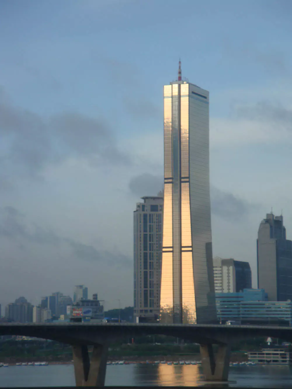 A cluster of modern high‑rise office buildings in Yeouido, Seoul, seen from a nearby park area with trees in the foreground.