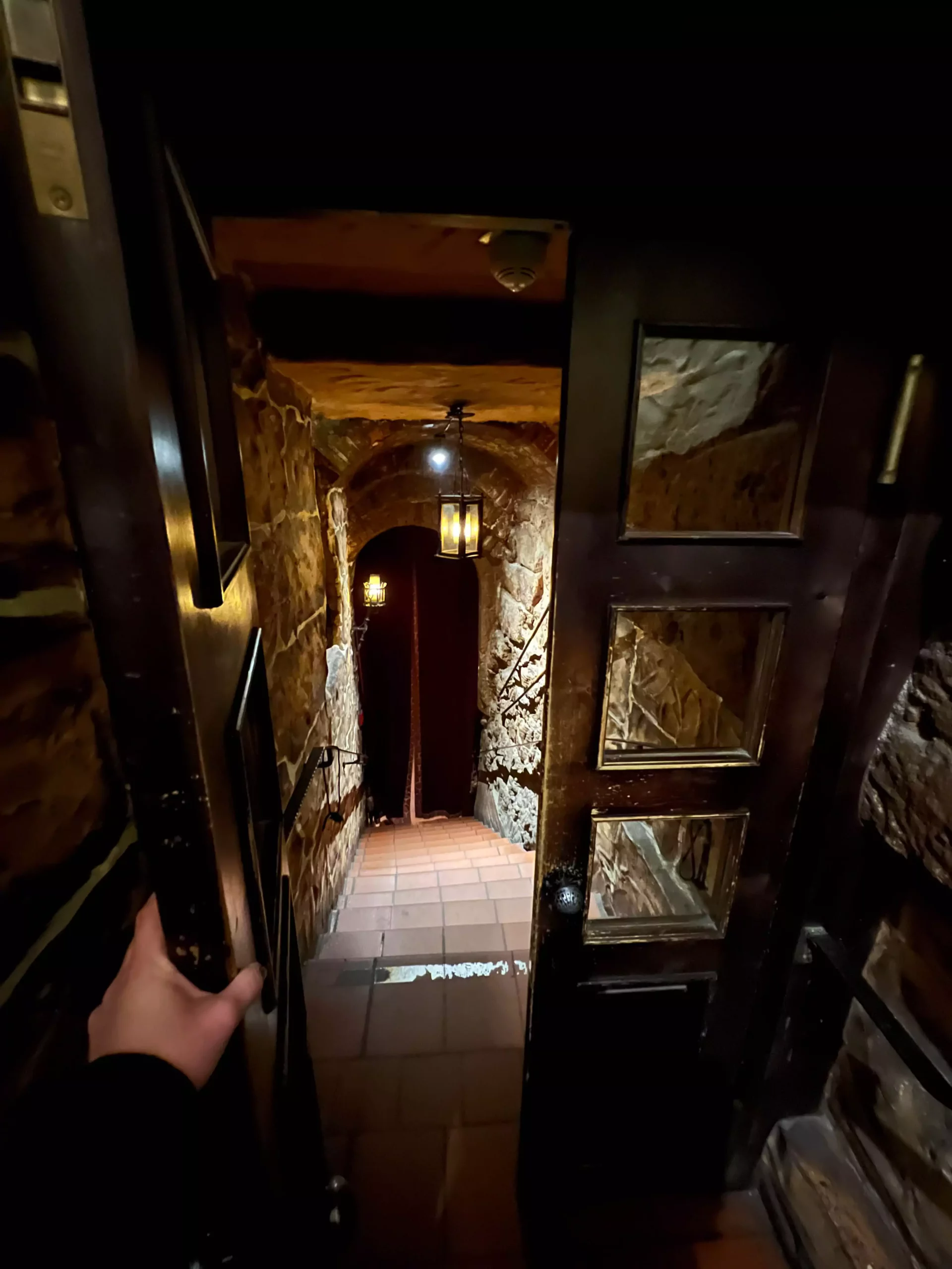 Stone stairwell leading down to Im Keller, a basement restaurant in Nuremberg, Germany. The dim lighting and aged stone walls set a mysterious, old-world tone as guests descend into the cozy underground space.