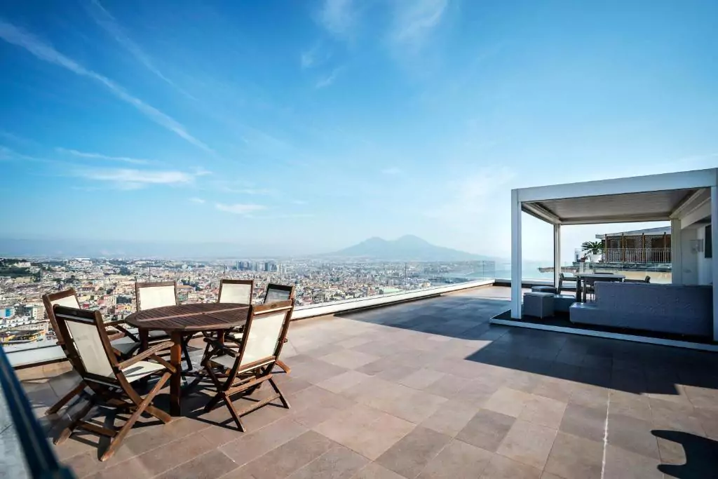 Terrazza Manù in Naples, Italy, featuring a panoramic rooftop terrace with lounge seating, potted plants, and sweeping views of the city and bay