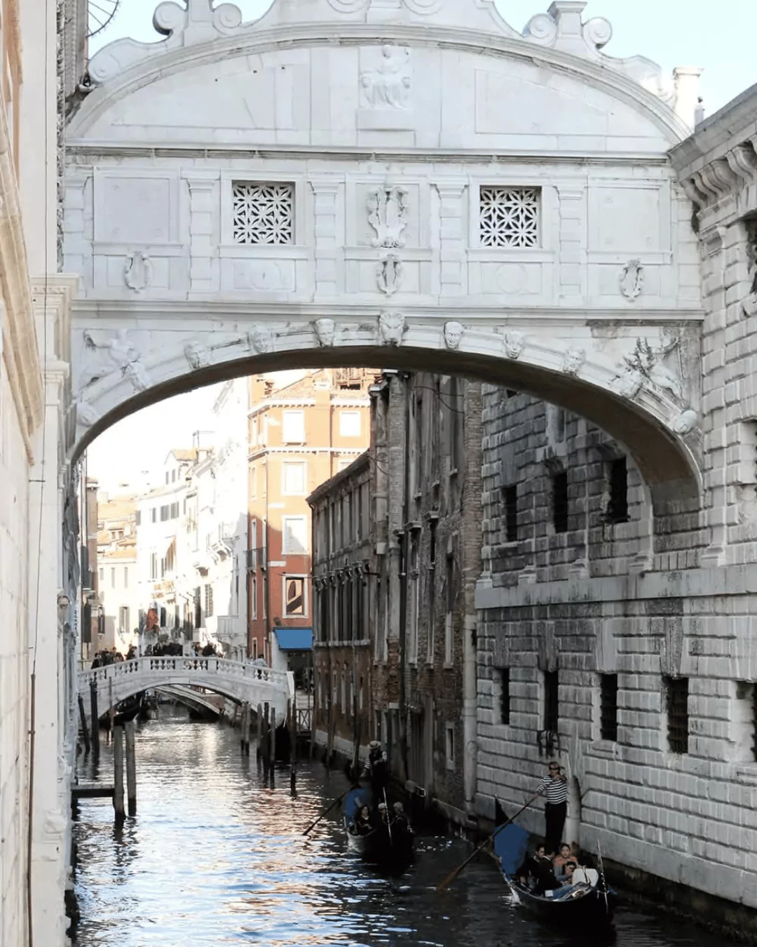 The Bridge of Sighs in Venice, Italy, an enclosed white limestone bridge with ornate windows, arching over a narrow canal connecting the Doge’s Palace to the historic prison.