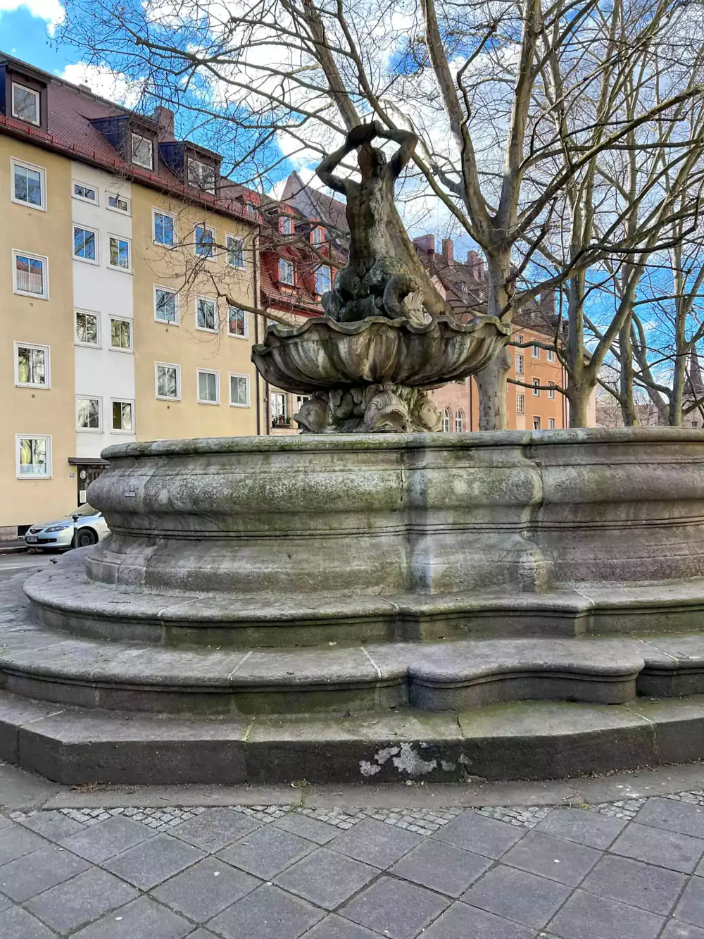 Tritonbrunnen in Nuremberg, a Baroque-style fountain featuring the sea god Triton wrestling a sea creature, surrounded by water jets and sculpted stone figures.