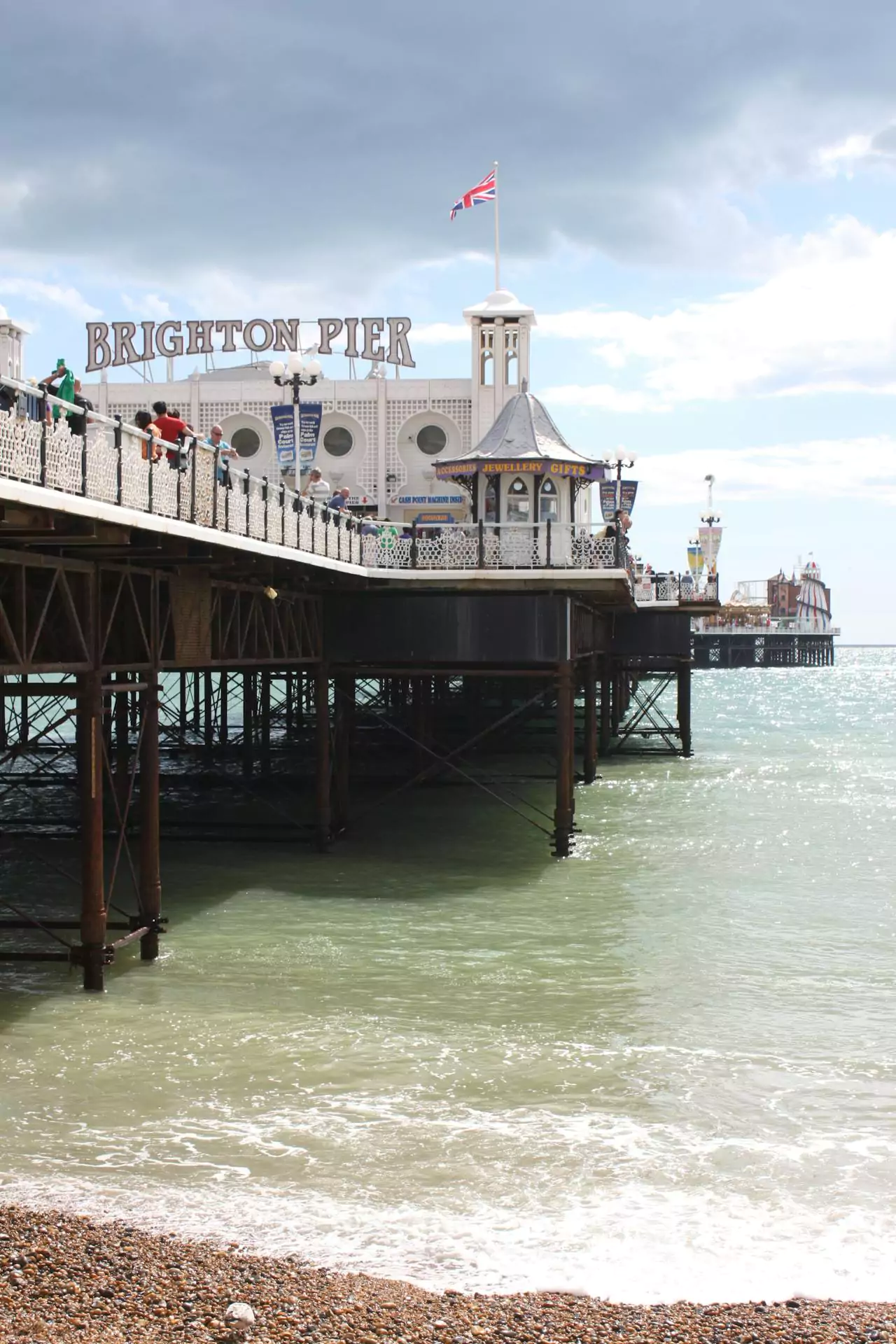 Brighton Pier in the UK, stretching into the sea with amusement rides, food stalls, and Victorian architecture, bustling with visitors against a coastal backdrop.