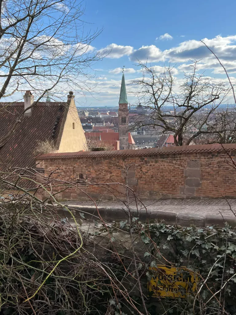 Panoramic view of Nuremberg’s Old Town from the Imperial Castle, with red-roofed medieval buildings, church spires, and winding cobblestone streets stretching across the historic cityscape.