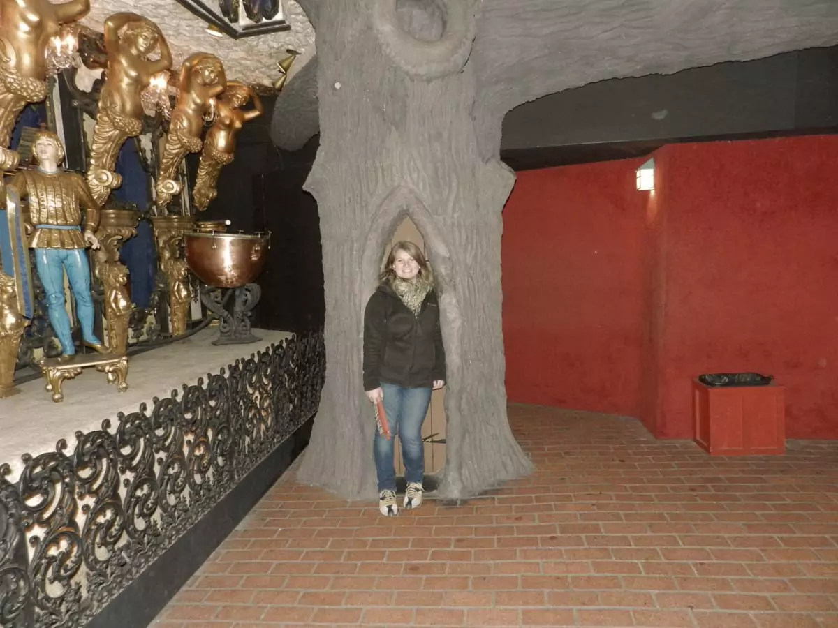 Katie standing inside a hollow tree trunk display at the House on the Rock in Wisconsin, blending whimsical nature and oddity as part of weird Wisconsin roadside attractions.