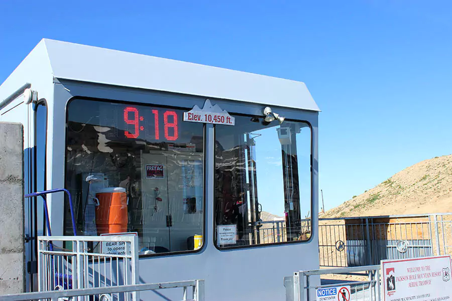 A sign at Jackson Hole Mountain Resort in Wyoming displaying the elevation of 10,450 feet against a backdrop of clear blue sky and mountain peaks. The sign marks the high-altitude summit of the ski area.