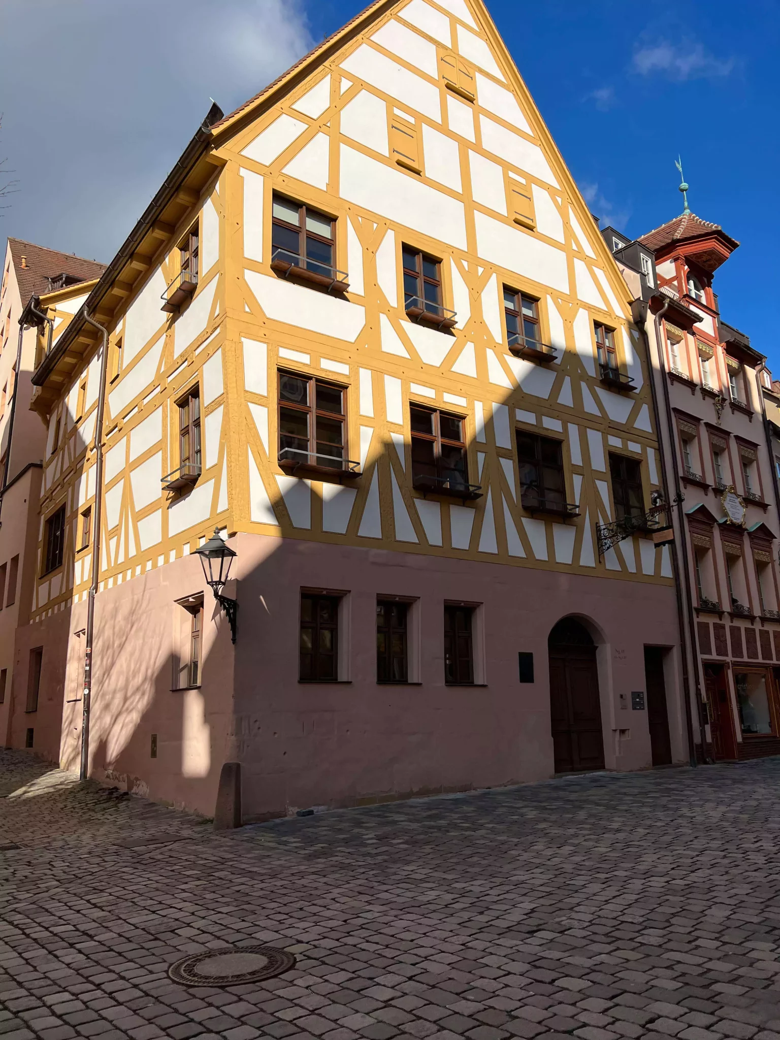 Charming yellow half-timbered house in Nuremberg’s old town, with exposed wooden beams and cobblestone street frontage.