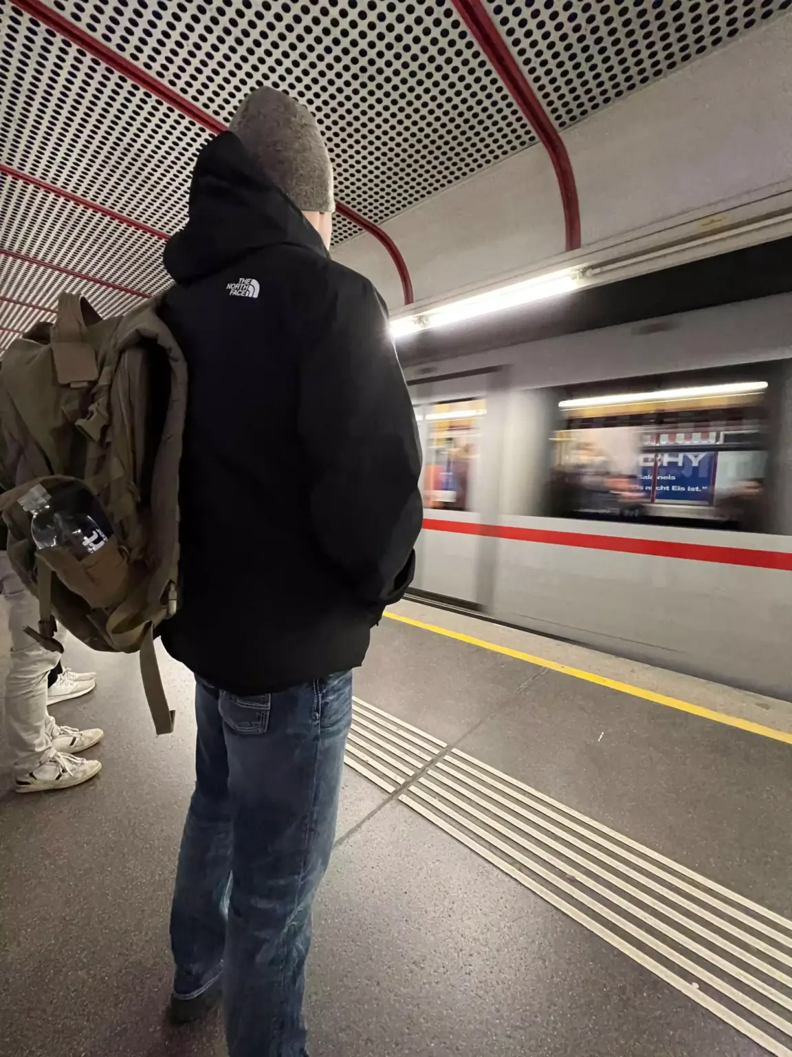 Zack stands on an underground train platform in Vienna, Austria, with modern signage and tiled walls surrounding him. The quiet platform and sleek design reflect the city’s efficient and clean public transit system.